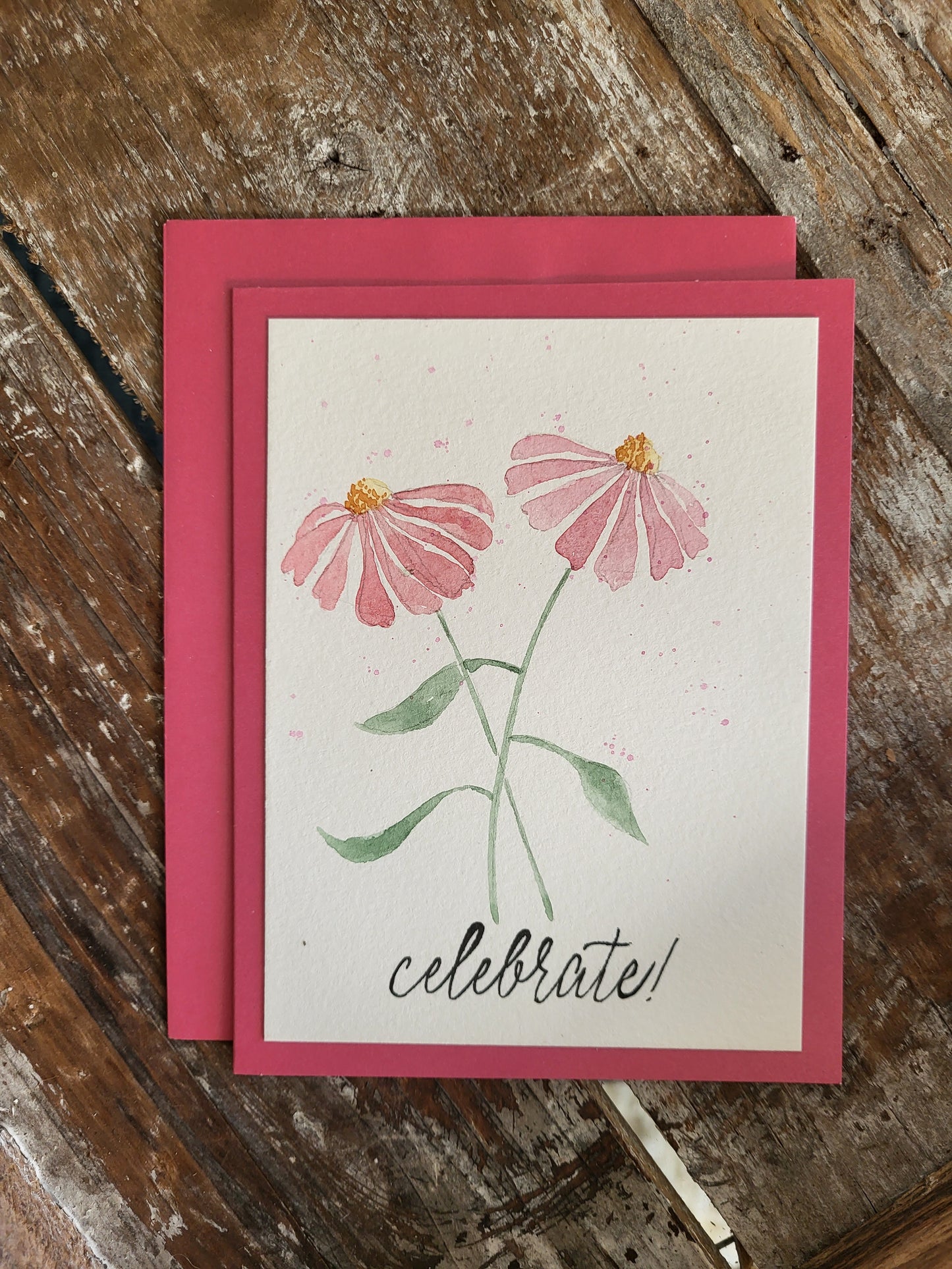 Two pink echinacea stems are hand painted on this dark pink card. It exclaims Celebrate!